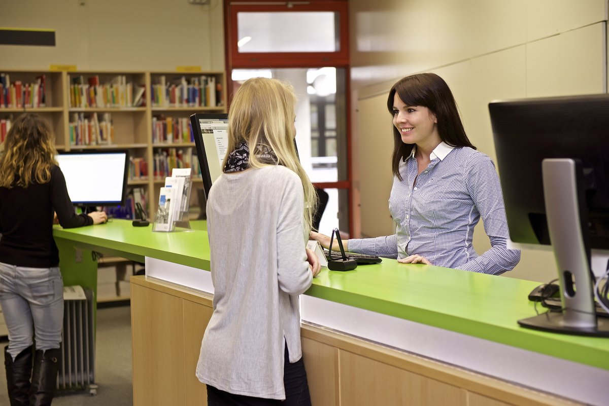 A student has a request and is greeted by an SSZ employee at the green counter